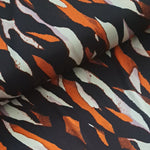   'Waves' polyester jersey with painted waves in orange and black on an ivory background. Portia Jersey is a soft handle, slinky jersey, perfect for dresses skirts and tops.   Colours may vary due to differences in computer settings. Sold in half metre increments at Fabric Focus.