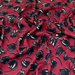 This soft and drapey polyester crepe fabric is a medium weight and is completely opaque, so perfect for sewing tops, skirts, dresses, trousers and jumpsuits. Wine background with tulip like floral motif. Available to buy in half metre increments at Fabric Focus.