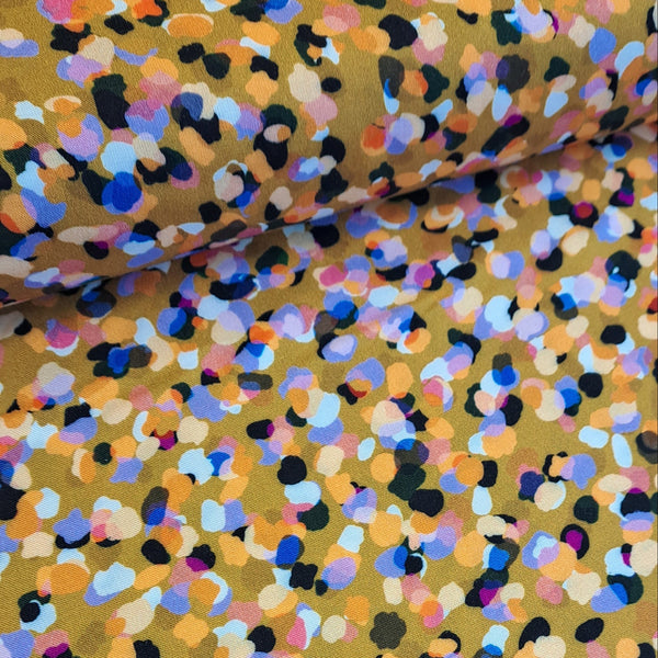 Gorgeous viscose print of multi-coloured confetti spots on a gold background. Wonderful for dressmaking, tops, skirts and wide leg trousers. Available to buy online at fabric Focus in half metre increments.