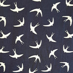 Ivory swallows in flight scattered on a navy blue background.  Perfect smooth weight of 100% cotton for dressmaking or craft projects. Available to buy in half metre increments at Fabric Focus Edinburgh.
