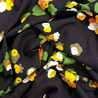 A stunning print of orange, yellow, white and green flowers on a black background. Perfect for wrap dresses, wide legged trousers and blouses. Manufacturer recommends 30 degree wash but please allow for shrinkage and test a piece before hand.  Sold in half metre increments at Fabric Focus Edinburgh.