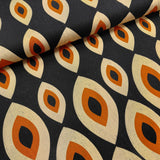 Fabric with a pattern of interlocking shapes in orange, beige, and black on a dark background.