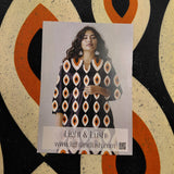 Card with a woman wearing a patterned dress on a decorative surface