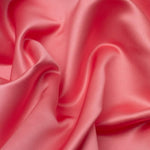 Duchess Satin fabric is a highly lustrous, smooth, very finely woven heavy non stretch satin.  This is the fashionable Coral colourway. Sold at Fabric Focus.