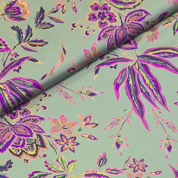 Polyester satin with a celadon green background with purple stylized floral pattern. Available to buy in half metre increments at Fabric Focus.