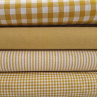 Incredibly versatile, our yarn-dyed* 100% cotton gingham fabric is ideal as a dress fabric and eternally popular for school uniforms, tablecloths, bunting, curtains, aprons, cushions, craft projects, Christmas decorations and much, much more. This being the mustard ochre colourway. Available to buy at Fabric Focus.