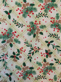 A close-up of a fabric or wallpaper pattern featuring green pine branches, holly leaves, red berries, and pinecones over a light beige plaid background.