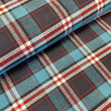 A close-up of folded plaid fabric with a tartan pattern in black, teal blue, red, white, and light gray.