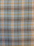 A close-up of a plaid fabric pattern featuring light blue, gray, brown, yellow, and white stripes.