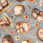 Cute little hedgehogs scattered with flowers on a grey background. Available to buy in quarter metre increments at Fabric Focus.
