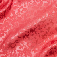 A beautiful soft polyester satin that has a subtle sateen sheen and a high gloss finish that makes up this floral jacquard. It has a high-end expensive look. Perfect for evening wear and day wear alike! This being the candy coral colourway.  Sold in half meter lengths at Fabric Focus.