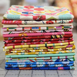 Stack of colorful fabric bundles on a cutting mat with a blurred background