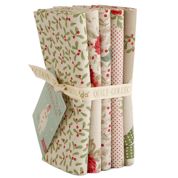 Set of fabric bundles with Christmas patterns in a cardboard holder on a white background