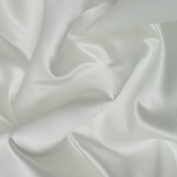 Duchess Satin fabric is a highly lustrous, smooth, very finely woven heavy non stretch satin. It has a very subtle sheen that is classic and elegant and very different in appearance to most satins which generally have a high gloss finish. This is the classic off white Porcelain. Sold in half meter lengths at Fabric Focus.