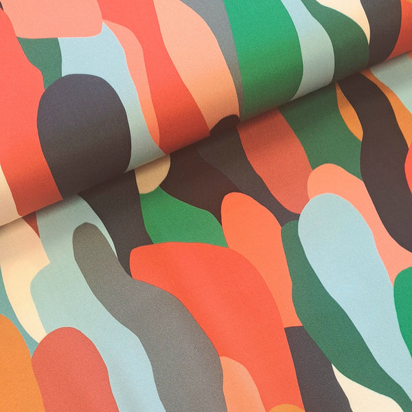 Gorgeous viscose twill of green, coral, black 'pebble' shapes on a cream background and available at Fabric Focus Edinburgh