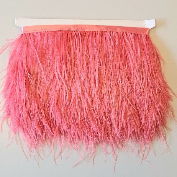 Super Luxurious Ostrich Feather trim, coloured and on co-ordinating coloured ribbon. Great for dressmaking, crafting, home decor and costume. A fashionable coral pink colour-way on a co-ordinating ribbon. Sold in metre increments