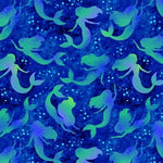 Beautiful silhouettes of long haired mermaids in shades of green and purple on a dark blue sea background. Available to buy in quarter metre increments at Fabric Focus Edinburgh